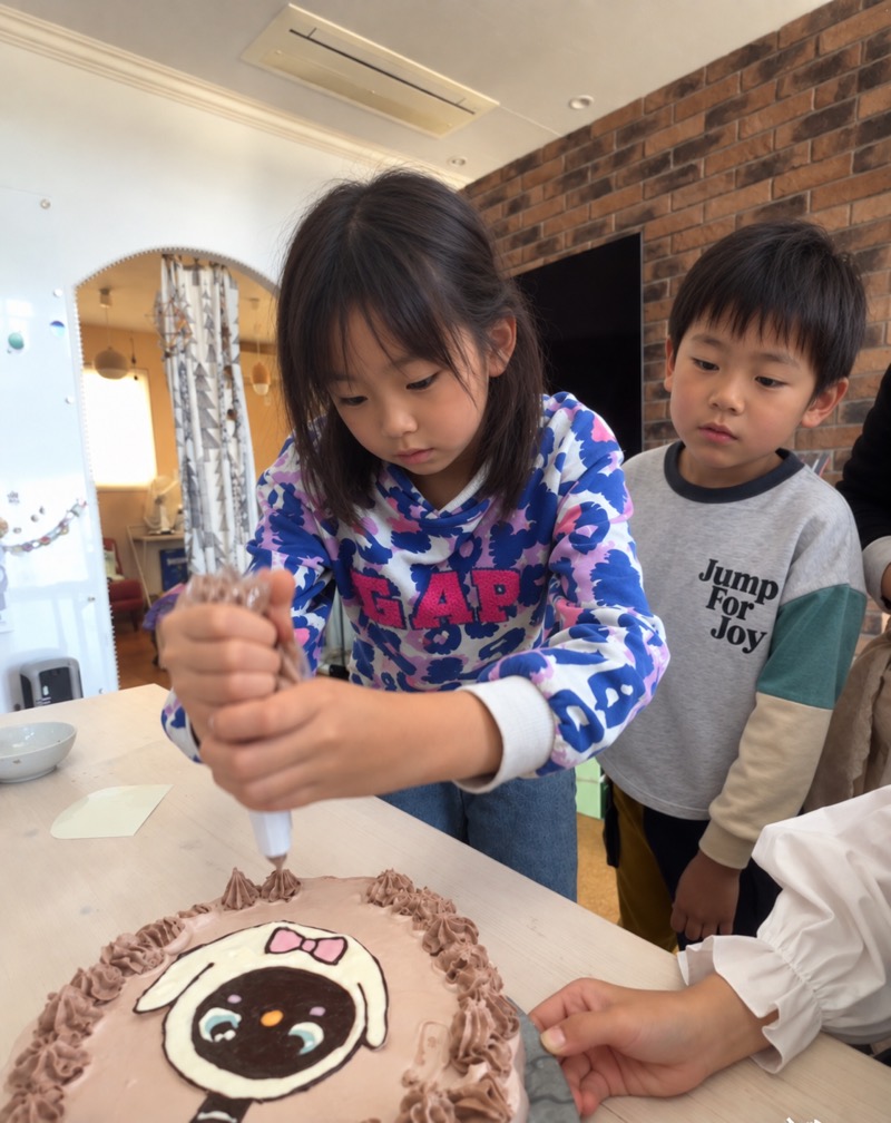 ケーキにクリームをしぼる子ども