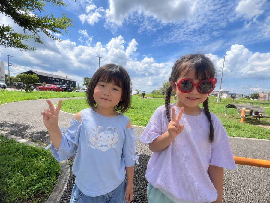 青空の公園でピースをする子どもたち